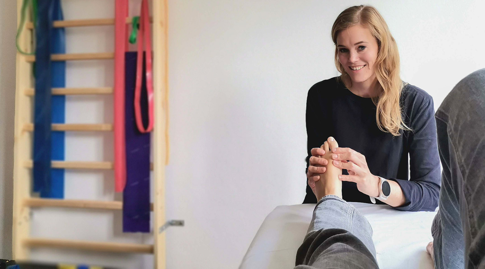 Physiotherapeutin massiert den Fuß einer Patientin
